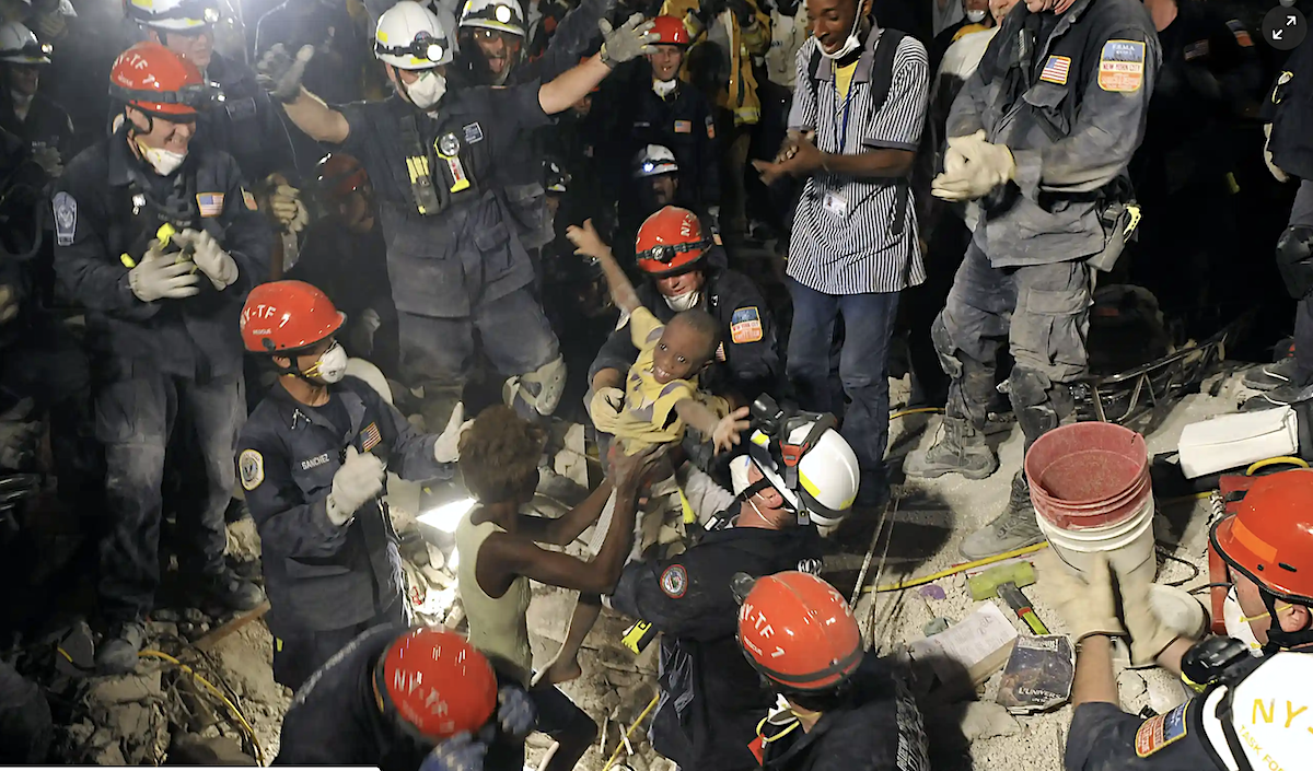 Спасатели вытащили из-под завалов живого ребенка. 14 января 2010. Фото Reuters