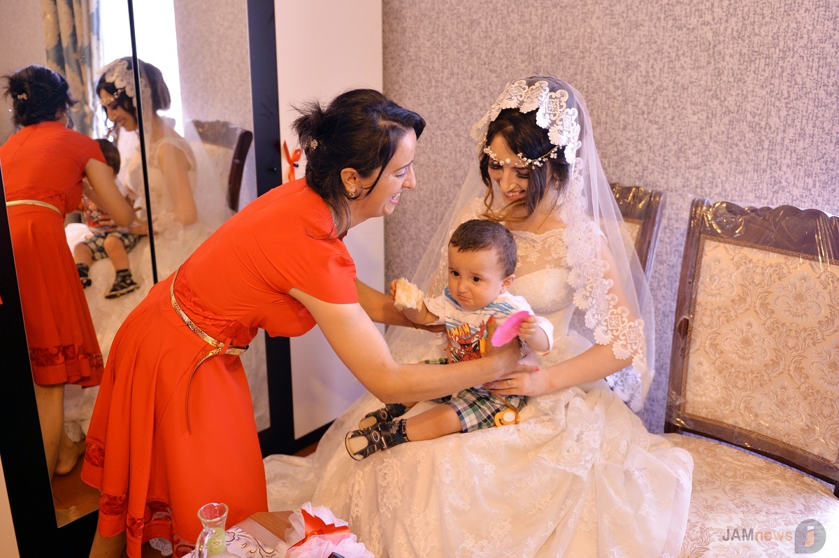 A young boy is placed on bride's knee so that her first born will be a boy. Traditional wedding in Azerbaijan, photo