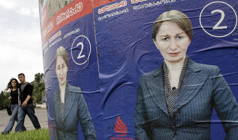 People walk past election posters in the centre of Tbilisi