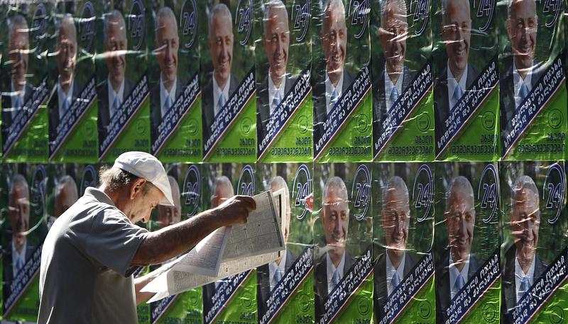 A man reads a newspaper near election posters in Tbilisi