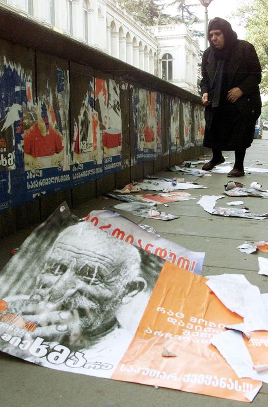 WOMAN PASSES TORN DOWN ELECTION POSTERS IN TBLISI.