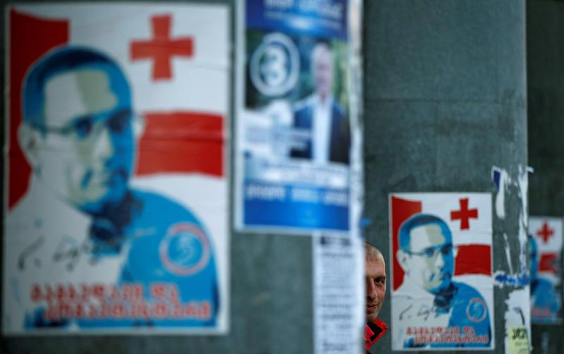 A man stands next to election posters ahead of the parliamentary elections in Tbilisi