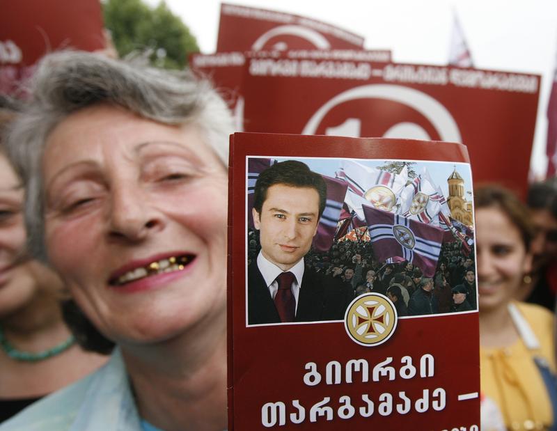 A woman holds portrait of Giorgi Targamdze, leader of Georgia's opposition Christian-Democracy Movement, during pre-election rally in Tbilisi