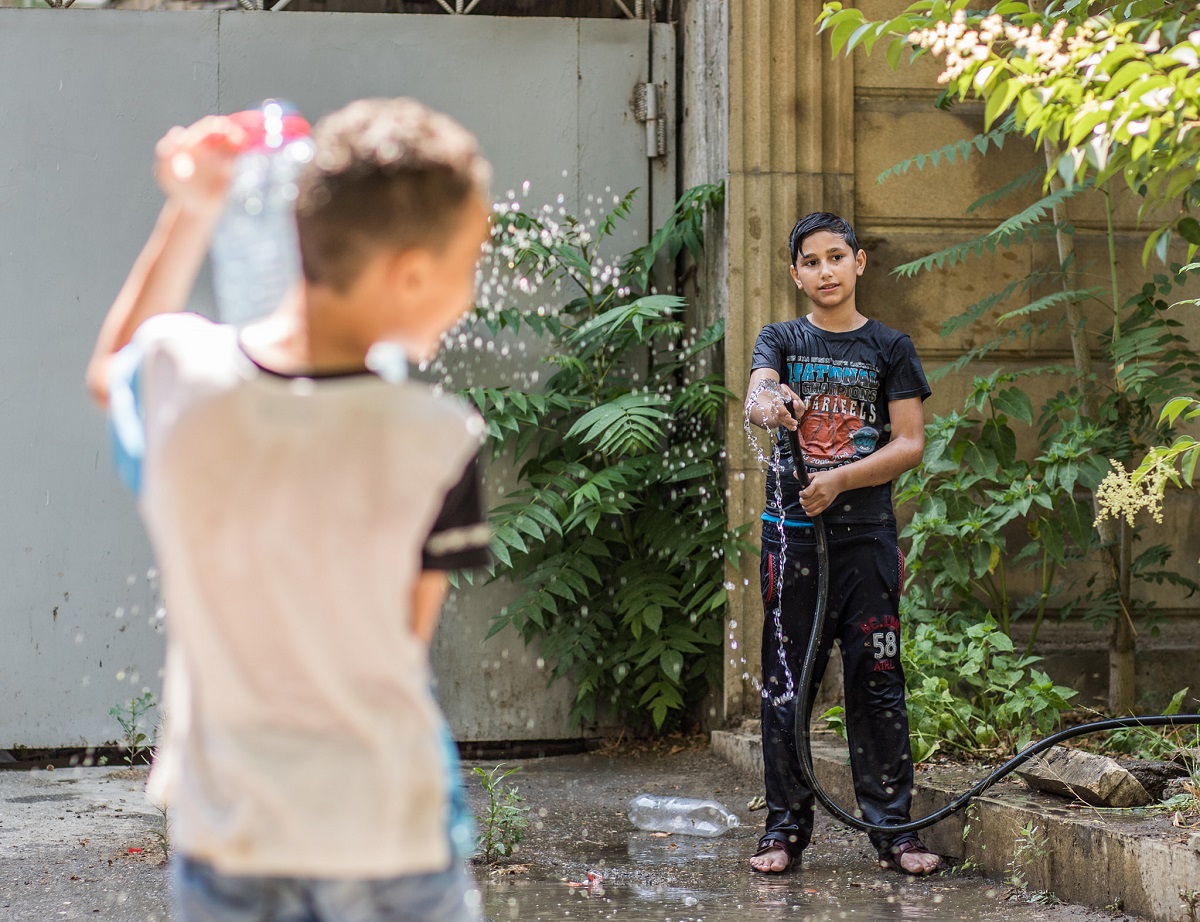 The children are playing with water on the streets of poor district in Baku