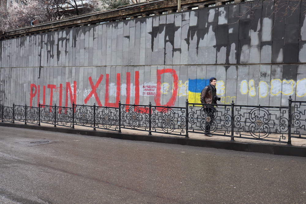 Rusiyalı siyasi mühacir Vasili Krestyaninov Putin əleyhinə yazının fonunda. Tbilisi, Gürcüstan. Foto: Malxaz Berdzenişvili, JAMnews