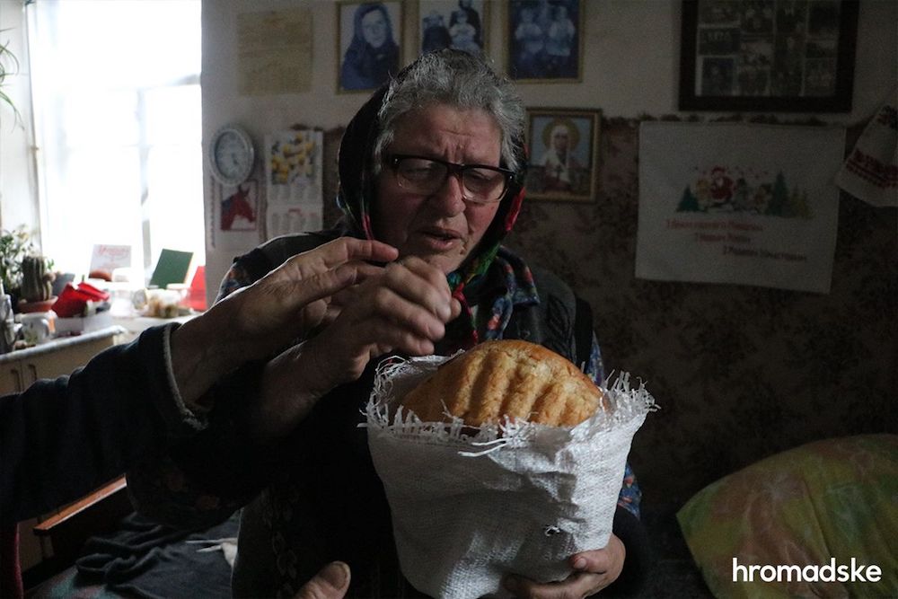 Погибшие мирные жители на войне в Украине. Жительница села Мотыжин Женя с хлебом, привезенным волонтерами.
Фото: Надежда Сухая / hromadske 