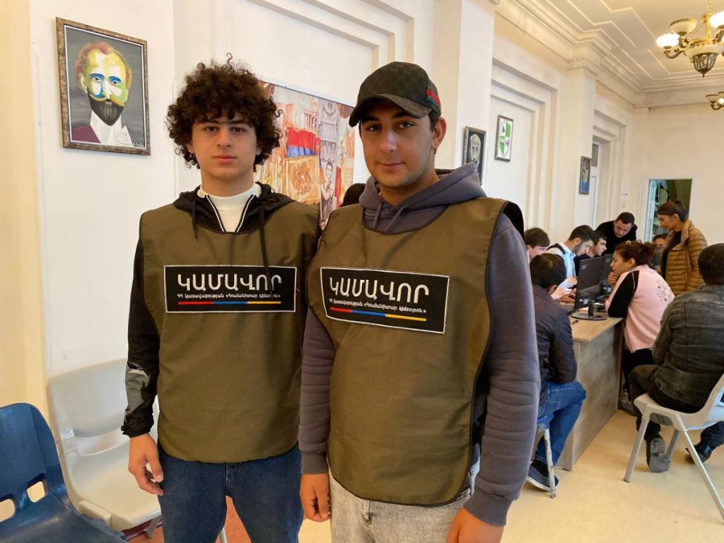 Gor and Arayik. They are wearing vests with the word "Volunteer" on them