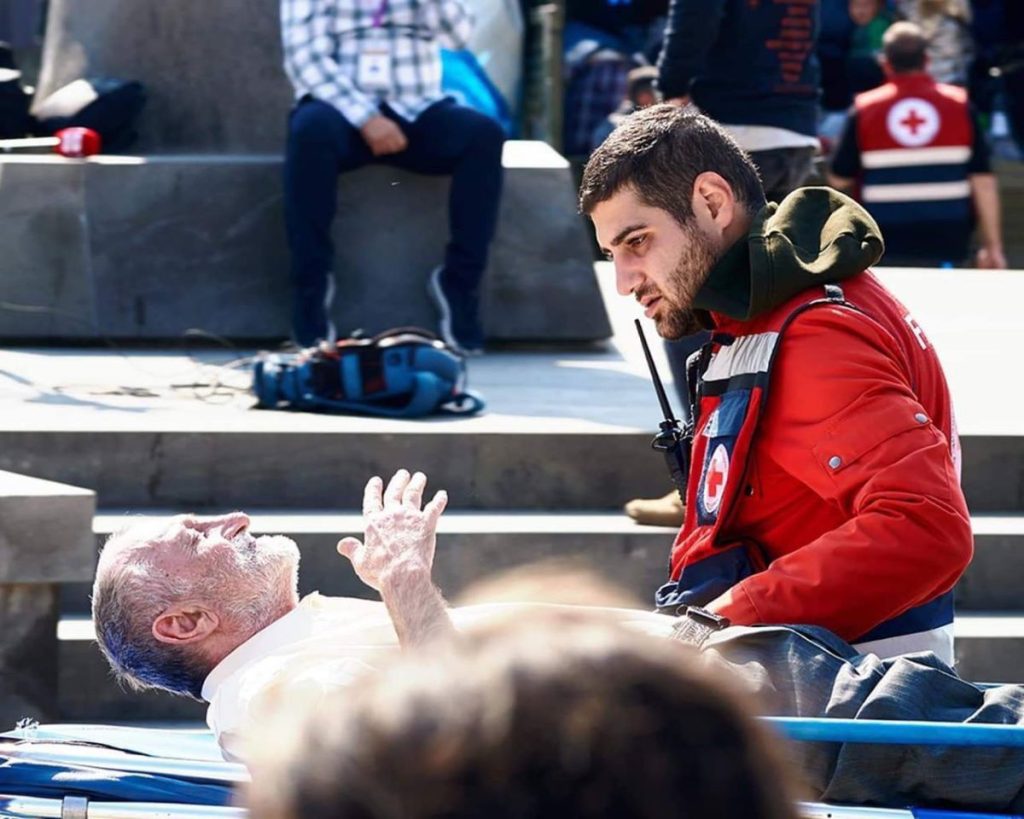 An elderly man on a stretcher speaks to an Armenian Red Cross volunteer