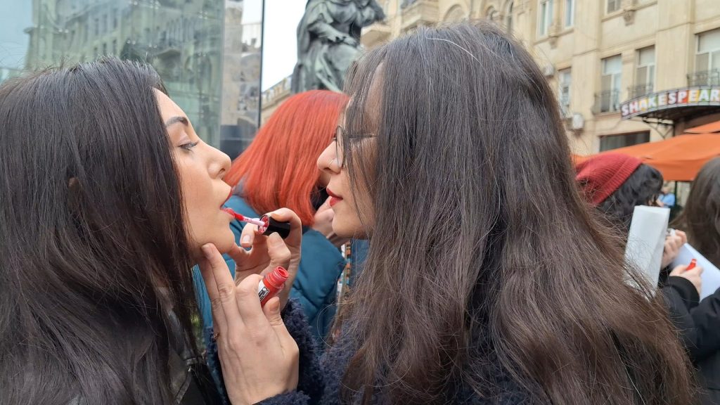 The feminists are applying red lipstick to their lips as a "symbol of female strength"