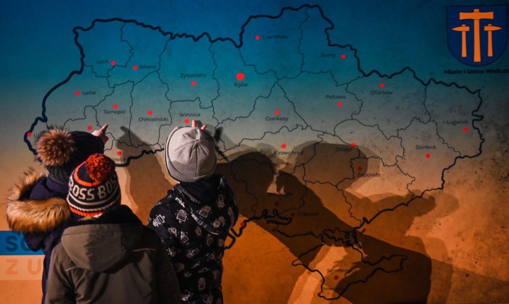 Ukrainian refugees in Europe. Ukrainian children, standing by a board with a map of Ukraine, excitedly point to their hometowns during the "Light for Ukraine" ceremony, which brought together refugees and locals to pray for peace. February 23, 2023, Grabie, Gmina Wieliczka, Poland. Photo by Artur Widak/NurPhoto via Getty Images