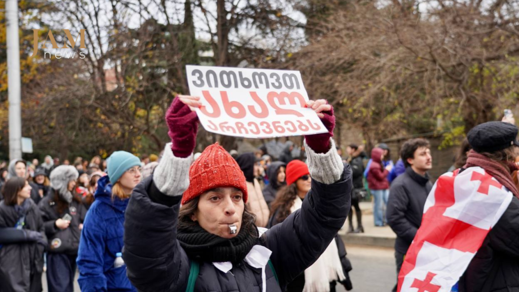 The sign reads: "We demand new parliamentary elections." December 13, 2024. Photo by David Pipia / JAMnews.