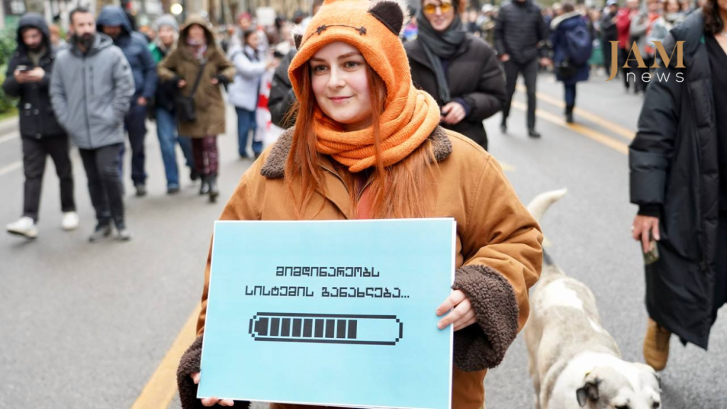 March of IT specialists. The sign reads: "System overload in progress." December 13, 2024. Photo by David Pipia / JAMnews.